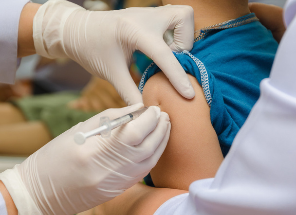 Médico inyectar la vacuna en el brazo del niño
 - Foto, imagen
