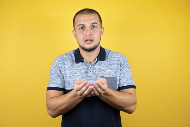 Russian man standing over insolated yellow background Smiling with hands palms together receiving or giving gesture. Hold and protection - Photo, Image