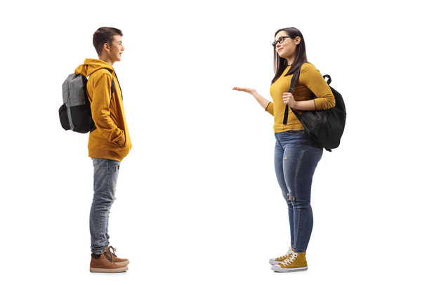 Full length profile shot of a male teenager talking to a female student isolated on white background - Photo, image