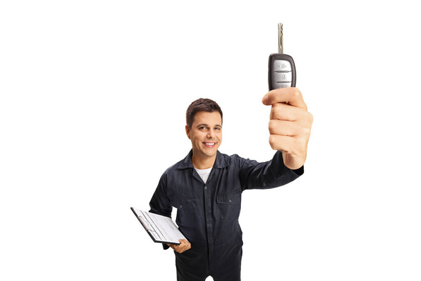 Auto mechanic smiling and holding a car key isolated on white background - Zdjęcie, obraz