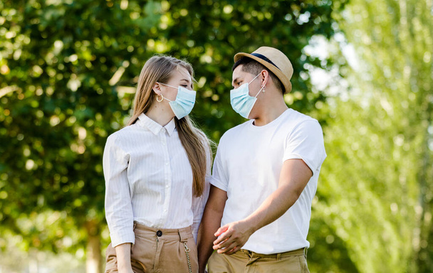 Paar mit Schutzmaske spaziert im Park - Foto, Bild