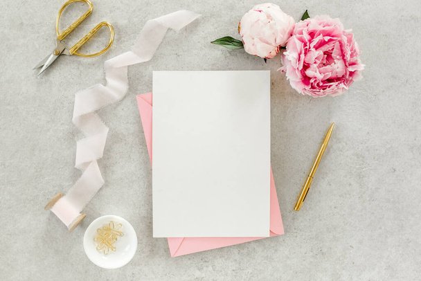 Mockup invitation, blank paper greeting card, pink envelope and peonies on gray stone table. Flower background. Flat lay, top view. - Foto, Imagem
