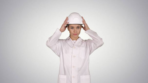 Woman engineer in white robe and white hard hat walking on gradi - Фото, изображение