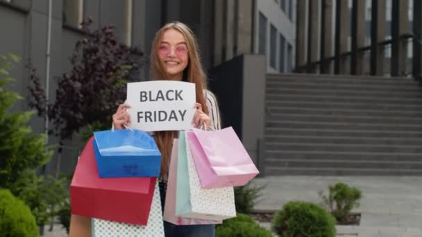 Joyful tiener meisje tonen Black Friday inscriptie, glimlachen, op zoek naar tevreden met lage prijzen - Video