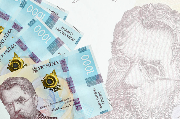 1000 billets de hryvnias ukrainiens sont empilés sur fond de gros billets semi-transparents. Fond d'entreprise abstrait avec espace de copie - Photo, image