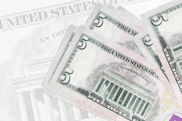 5 US dollar biljetten liggen in stapel op de achtergrond van grote semi-transparante bankbiljet. Abstracte presentatie van de nationale munt. Bedrijfsconcept - Foto, afbeelding