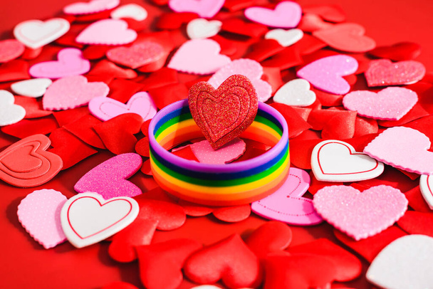 Багатокольоровий ЛГБТ символ на тлі романтичних червоних сердець, валентинки для одностатевих пар.. - Фото, зображення