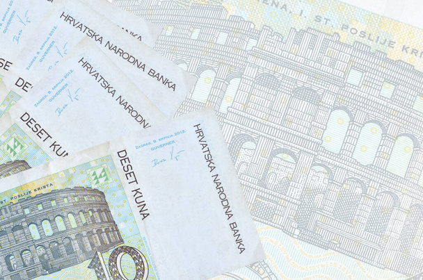 10 Kroatische kuna biljetten liggen op de achtergrond van een groot semi-transparant bankbiljet. Abstract zakelijke achtergrond met kopieerruimte - Foto, afbeelding