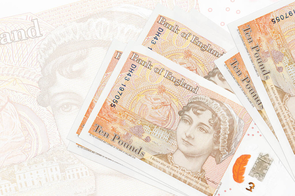 Tien Britse pond biljetten liggen in stapel op de achtergrond van een groot semi-transparant bankbiljet. Abstracte presentatie van de nationale munt. Bedrijfsconcept - Foto, afbeelding