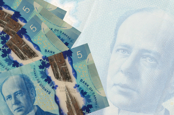 5 billetes de dólares canadienses se encuentra en la pila en el fondo de gran billete semitransparente. Fondo de negocio abstracto con espacio de copia - Foto, Imagen