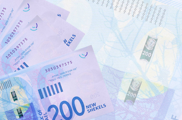 200 billetes israelíes nuevos shekels se encuentran en la pila en el fondo de un gran billete semitransparente. Fondo de negocio abstracto con espacio de copia - Foto, imagen
