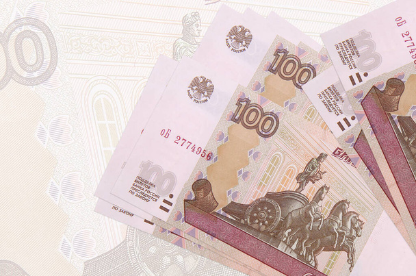 100 billets de roubles russes sont empilés sur fond de gros billets semi-transparents. Présentation synthétique de la monnaie nationale. Concept d'entreprise - Photo, image