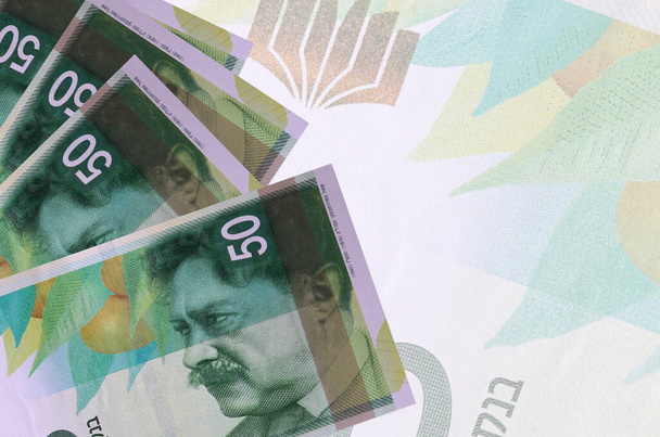 50 Israëlische nieuwe shekels biljetten liggen in stapel op de achtergrond van grote semi-transparante bankbiljet. Abstract zakelijke achtergrond met kopieerruimte - Foto, afbeelding