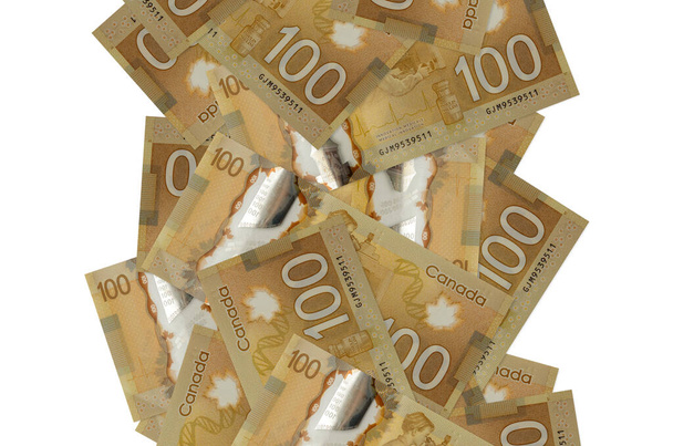 100 kanadische Dollarscheine fliegen vereinzelt auf weiß herunter. Viele Banknoten mit weißem Kopierraum links und rechts - Foto, Bild