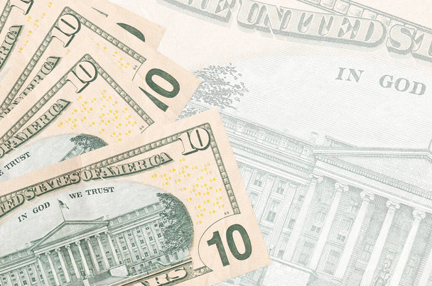 10 Amerikaanse dollars biljetten liggen in stapel op de achtergrond van grote semi-transparante bankbiljetten. Abstract zakelijke achtergrond met kopieerruimte - Foto, afbeelding