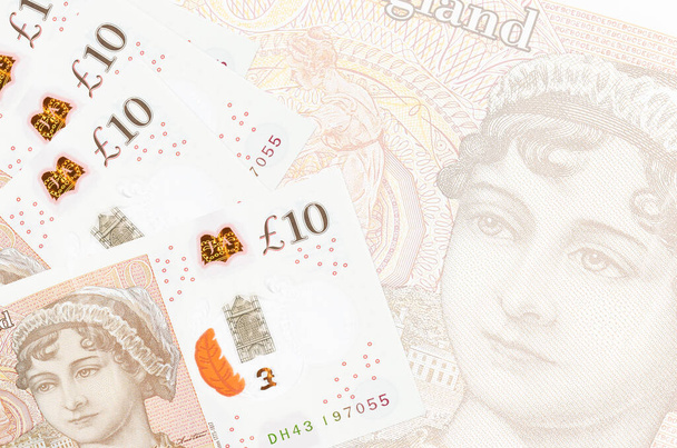 10 brytyjskich banknotów leży w stosach na tle dużego półprzezroczystego banknotu. Streszczenie kontekstu biznesowego z przestrzenią do kopiowania - Zdjęcie, obraz