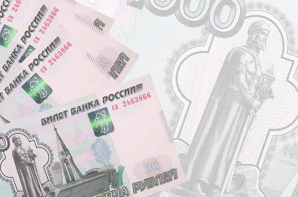 1000 Russische roebel biljetten liggen in stapel op de achtergrond van een groot semi-transparant bankbiljet. Abstract zakelijke achtergrond met kopieerruimte - Foto, afbeelding