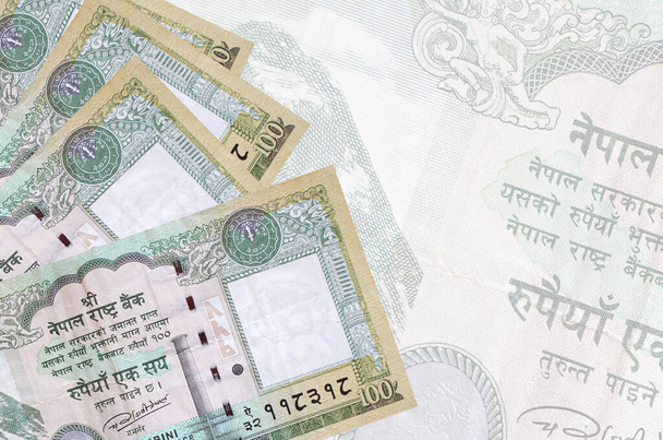 100 billetes de rupias nepalíes se encuentra en la pila en el fondo de un gran billete semitransparente. Fondo de negocio abstracto con espacio de copia - Foto, Imagen