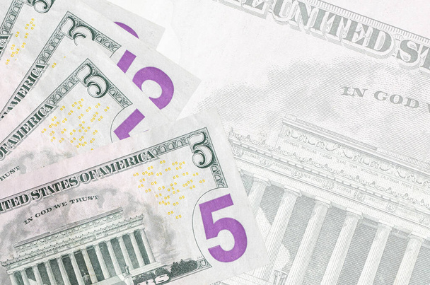 5-Dollar-Scheine liegen gestapelt auf dem Hintergrund der großen halbtransparenten Banknote. Abstrakter geschäftlicher Hintergrund mit Kopierraum - Foto, Bild