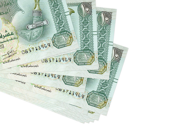 10 банкнот дирхамов ОАЭ лежат в небольшом пакете или упаковке, изолированной на белом. Макет с копировальным пространством. Концепция бизнеса и обмена валюты - Фото, изображение