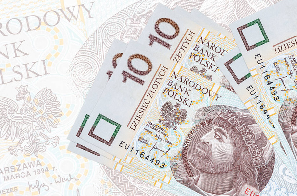 10 Poolse zloty biljetten liggen in stapel op de achtergrond van grote semi-transparante bankbiljet. Abstracte presentatie van de nationale munt. Bedrijfsconcept - Foto, afbeelding