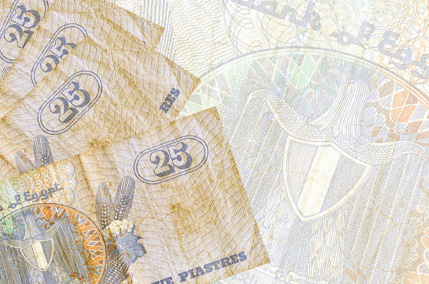 25 billetes de piastras egipcias se encuentra en la pila en el fondo de gran billete semitransparente. Fondo de negocio abstracto con espacio de copia - Foto, Imagen
