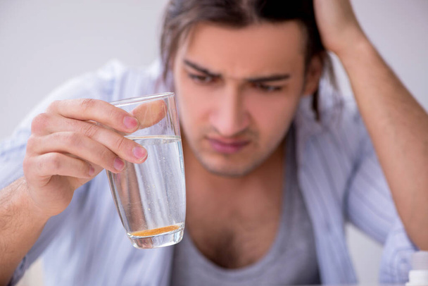 Jonge mannelijke alcoholist die thuis whisky drinkt - Foto, afbeelding