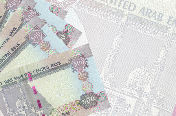 500 billetes dirhams de los Emiratos Árabes Unidos se encuentran en la pila sobre el fondo de un gran billete semitransparente. Fondo de negocio abstracto con espacio de copia - Foto, Imagen