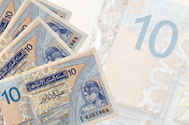 10 banknotów denarów tunezyjskich leży w stosach na tle dużego półprzezroczystego banknotu. Streszczenie kontekstu biznesowego z przestrzenią do kopiowania - Zdjęcie, obraz
