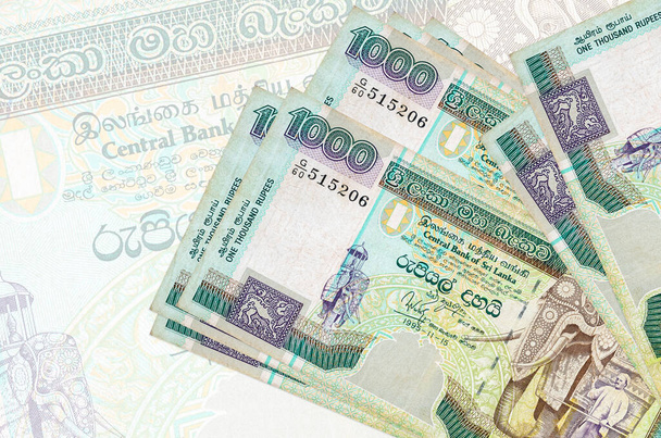 1000 Sri Lankaanse roepies biljetten liggen in stapel op de achtergrond van grote semi-transparante bankbiljet. Abstracte presentatie van de nationale munt. Bedrijfsconcept - Foto, afbeelding