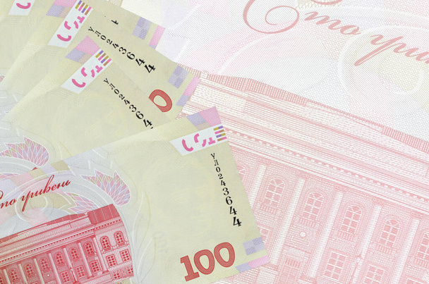 100 Ukrayna hrivniası banknotları büyük yarı şeffaf banknotların arka planında duruyor. Kopyalama alanı olan soyut iş arkaplanı - Fotoğraf, Görsel