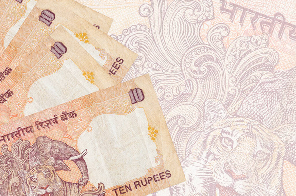 10 billetes de rupias indias se encuentra en la pila en el fondo de gran billete semitransparente. Fondo de negocio abstracto con espacio de copia - Foto, Imagen