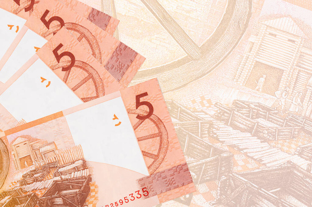 Τα χαρτονομίσματα των 5 ρουβλίων Λευκορωσίας βρίσκονται σε στοίβα στο φόντο ενός μεγάλου ημι-διαφανούς τραπεζογραμματίου. Αφηρημένο επιχειρηματικό υπόβαθρο με αντίγραφο χώρου - Φωτογραφία, εικόνα