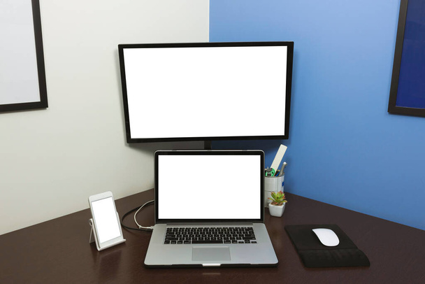 Настольный ноутбук и мобильный телефон с чистым текстовым экраном в офисе на деревянном столе. Концептуальное изображение рабочего пространства ноутбука.  - Фото, изображение