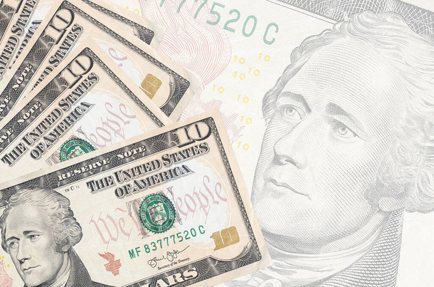 Τα χαρτονομίσματα των 10 δολαρίων ΗΠΑ βρίσκονται σε στοίβα στο φόντο ενός μεγάλου ημι-διαφανούς τραπεζογραμματίου. Αφηρημένο επιχειρηματικό υπόβαθρο με αντίγραφο χώρου - Φωτογραφία, εικόνα
