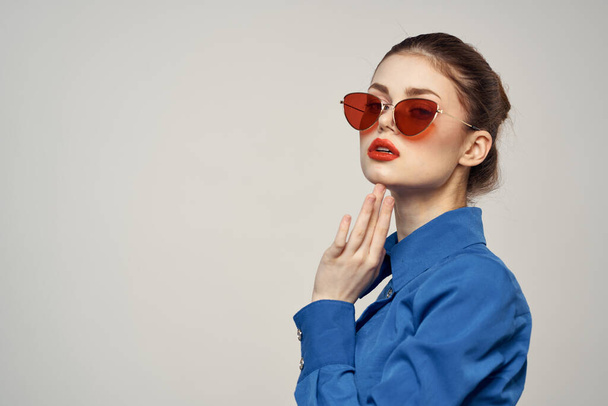 Portré egy nő napszemüvegben és egy kék ing egy könnyű háttér kivágott kilátás Model Copy Space - Fotó, kép