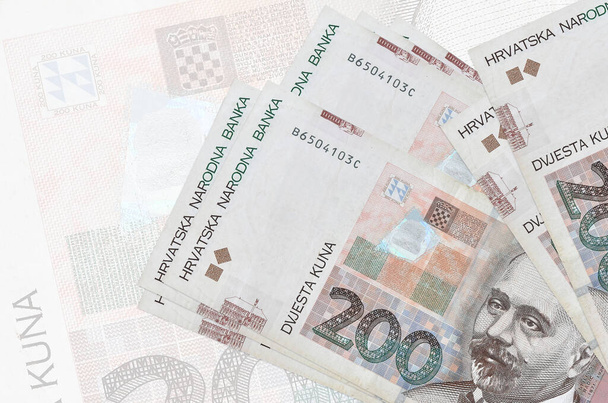 200 Kroatische kuna biljetten liggen op de achtergrond van een groot semi-transparant bankbiljet. Abstracte presentatie van de nationale munt. Bedrijfsconcept - Foto, afbeelding