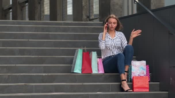Lány ül a lépcsőn táskák beszél mobiltelefon eladó bevásárló központ Fekete péntek - Felvétel, videó