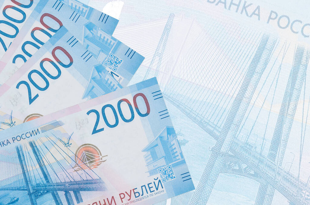 2000 Russische roebel biljetten ligt in stapel op de achtergrond van grote semi-transparante bankbiljet. Abstract zakelijke achtergrond met kopieerruimte - Foto, afbeelding