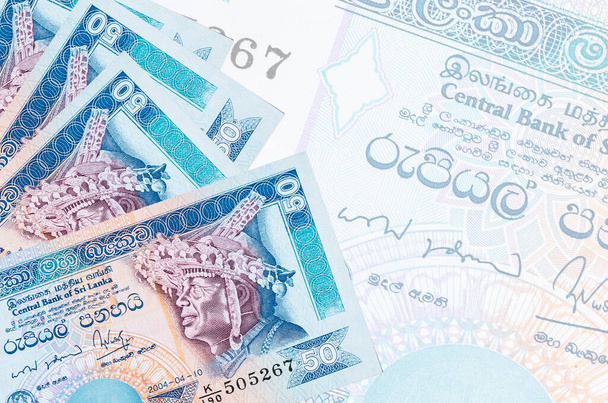 50 банкнот Шри-Ланки лежат в стопке на фоне большой полупрозрачной банкноты. Аннотация бизнес-фон с копировальным пространством - Фото, изображение
