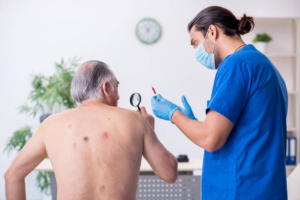 Vieil homme visitant un jeune homme médecin dermatologue - Photo, image
