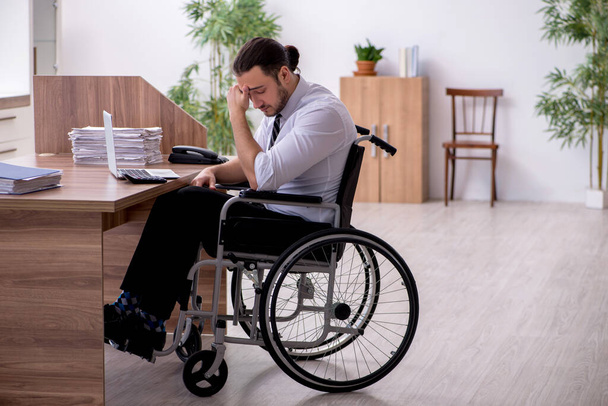 Jonge gehandicapte werknemer die op het werk lijdt - Foto, afbeelding