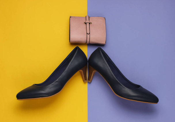 Zapatos de tacón alto de cuero, billetera sobre fondo amarillo púrpura. Estudio de tiro de moda. Vista superior - Foto, Imagen
