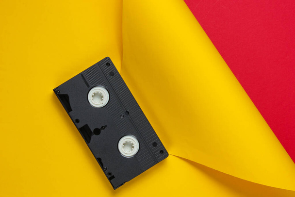 Video cassette tape on red yellow creative studio background. Minimalistic fashion shot. - Photo, Image