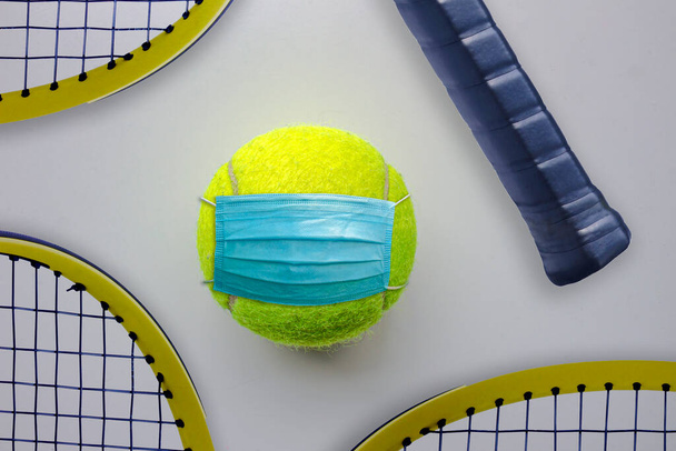 A tennis ball with a face mask and tennis racquets around - Foto, imagen