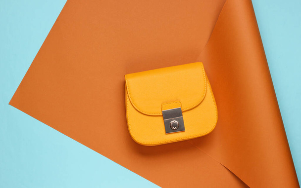 Žlutá kožená taška na zabaleném papíře. Pastel barevný trend, minimalistická krása a módní zátiší. Horní pohled - Fotografie, Obrázek
