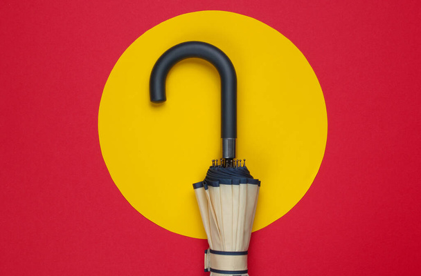 Umbrella hook on a red background with a yellow circle in the middle. Minimalistic fashion concept. - Photo, Image