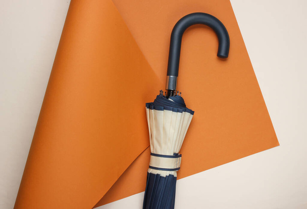 Umbrella hook on colored folded paper background. Minimalistic fashion still life. Flat lay. Top view - Foto, imagen