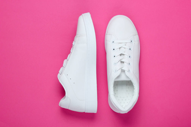 Stylish white sneakers on pink paper background with pink circle. Minimalistic fashion concept. Top view - Photo, Image