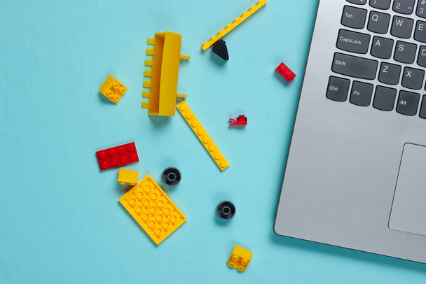 Ordenador portátil y ladrillos de juguete sobre un fondo azul. Concepto de infancia. Vista superior - Foto, imagen